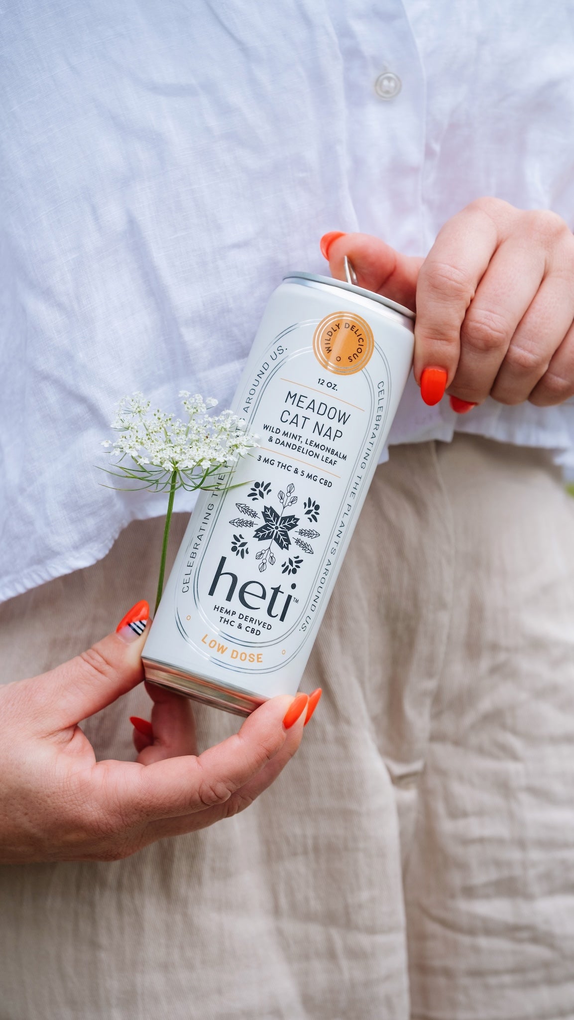 Person holding Heti CBD & THC mocktail beverage can in flavor Meadow Cat Nap which is dandelion leaf, lemon balm and wild mint